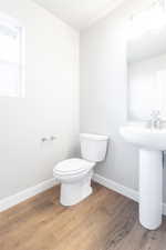 Bathroom featuring baseboards, toilet, and wood finished floors