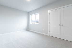 Unfurnished bedroom with visible vents, baseboards, a closet, and light colored carpet