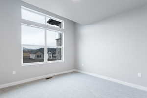 Spare room featuring a healthy amount of sunlight, visible vents, baseboards, and carpet flooring