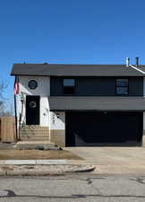 View of front of home featuring a garage, driveway, fence, and brick siding