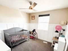 Bedroom featuring a wainscoted wall, dark colored carpet, and a ceiling fan