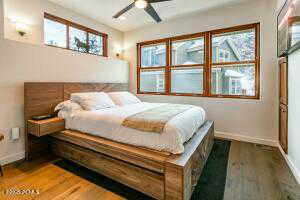 Bedroom with ceiling fan, multiple windows, and hardwood / wood-style flooring