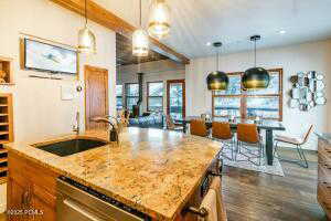 Kitchen featuring decorative light fixtures, sink, stainless steel dishwasher, and light stone countertops