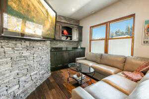 Living room with a stone fireplace and hardwood / wood-style floors