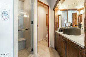 Bathroom featuring toilet, vanity, and a shower with door