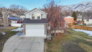 View of front of home with an attached garage, a mountain view, fence, concrete driveway, and a front yard