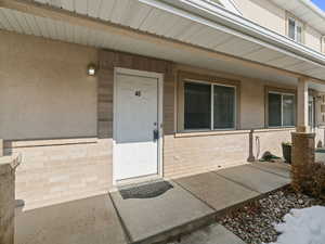 Doorway to property featuring stucco siding, a porch, and brick siding