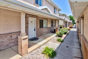 View of exterior entry with covered porch, stucco siding, and brick siding