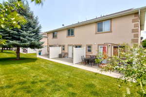 Rear view of property featuring stucco siding, a patio, and a lawn