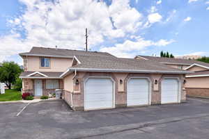 Townhome / multi-family property featuring community garages, stucco siding, and a shingled roof