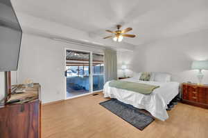 Primary Bedroom with light wood-style floors, access to outside, ceiling fan, and baseboards