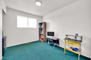 Interior space with visible vents, dark carpet, and baseboards