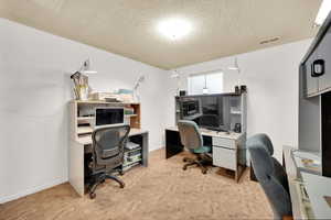 Office space with baseboards, visible vents, and a textured ceiling