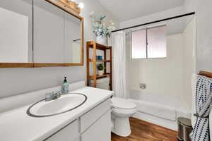 Full bathroom featuring shower / bath combo with shower curtain, vanity, toilet, and wood finished floors