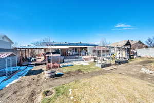 Back of house featuring a hot tub, fence, a deck, and a playground