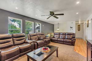 Living room featuring recessed lighting, visible vents, light wood-style flooring, a ceiling fan, and a textured ceiling