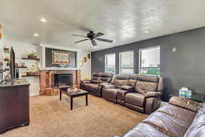 Living area featuring ceiling fan, a textured ceiling, recessed lighting, light carpet, and a fireplace