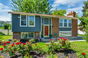 Bi-level home with brick siding, fence, and a chimney