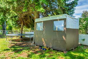 View of shed featuring a trampoline and a fenced backyard