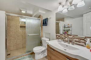 Full bath featuring tasteful backsplash, a stall shower, vanity, and toilet