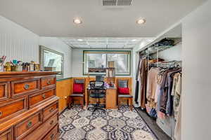 Interior space with a wainscoted wall, recessed lighting, light colored carpet, visible vents, and wood walls