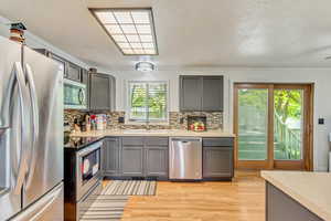 Kitchen with light countertops, appliances with stainless steel finishes, a sink, and gray cabinetry