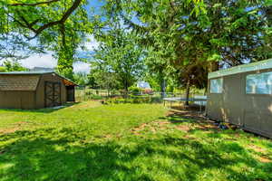 View of yard with a trampoline, an outbuilding, a fenced backyard, and a storage shed