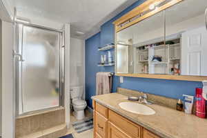 Full bath with toilet, a shower with door, vanity, and tile patterned floors