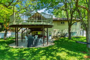 Back of property with a deck, a patio, fence, stairs, and a yard