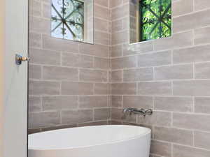 Full bath featuring tile patterned flooring, a freestanding tub, and tile walls