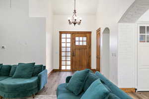 Foyer entrance featuring baseboards, light wood-style flooring, arched walkways, and a notable chandelier