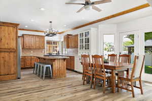 Interior space featuring a breakfast bar area, light countertops, a center island, brown cabinetry, and pendant lighting