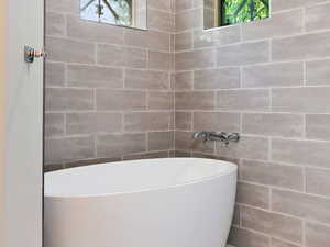 Full bath featuring a freestanding bath and tile walls