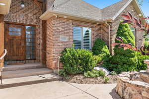 Entrance to property featuring roof with shingles and brick siding