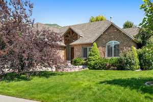 View of front of property featuring brick siding, a front lawn, and a shingled roof