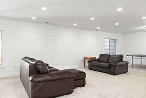 Living area with recessed lighting, light colored carpet, and baseboards