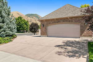 View of front facade featuring driveway, a garage, a mountain view, and brick siding