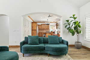 Living room featuring baseboards, arched walkways, ceiling fan, light wood-style floors, and recessed lighting