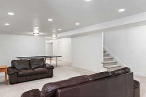 Living room featuring light carpet, recessed lighting, stairs, and baseboards