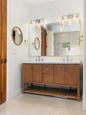 Full bathroom with double vanity, a sink, and baseboards