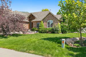 View of front of house featuring a shingled roof, brick siding, and a front lawn