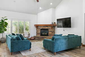 Living area with high vaulted ceiling, a fireplace, light wood-style flooring, and recessed lighting