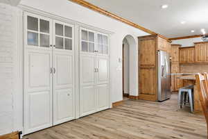 Kitchen featuring stainless steel fridge, arched walkways, a breakfast bar area, light countertops, and crown molding