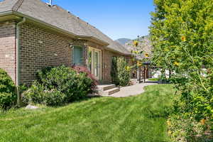 Back of property with a yard, a patio area, a mountain view, and brick siding