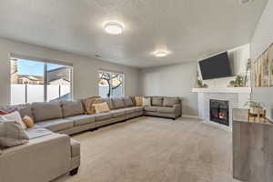 Living room with a brick fireplace, light carpet, and a textured ceiling