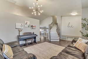 Living room featuring an inviting chandelier, visible vents, stairway, and dark wood-style flooring