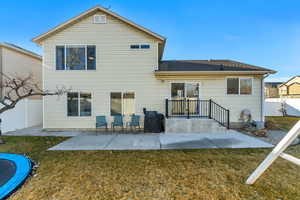 Back of house with a yard, a trampoline, fence, and a patio