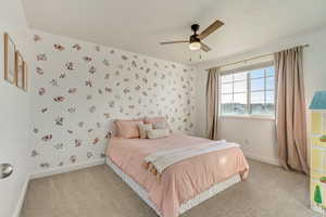 Bedroom featuring light carpet, wallpapered walls, ceiling fan, and baseboards