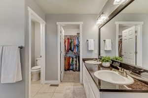 Full bathroom with tile patterned floors, a sink, toilet, and double vanity