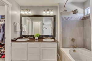 Full bath with double vanity, bathtub / shower combination, a walk in closet, and a sink